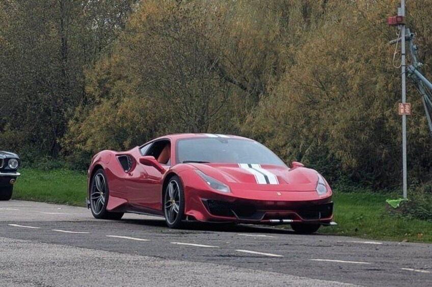 A red sports car parked on a road with trees in the background. 4