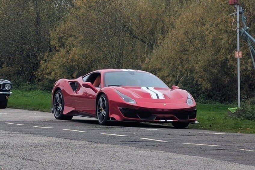 A red sports car parked on a road with trees in the background. 3