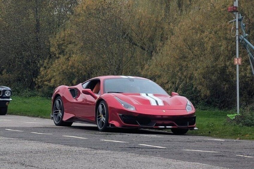 A red sports car parked on a road with trees in the background. 3