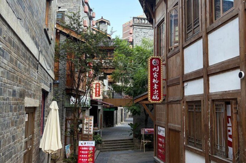 A narrow alley with traditional wooden buildings, a red signboard, and a small shop entrance. 4