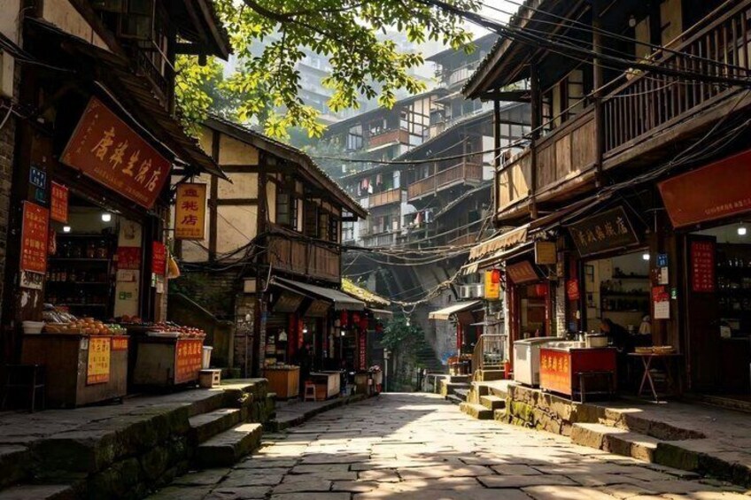 A narrow street lined with traditional wooden buildings, some with signage in a foreign language, and a stone-paved path. 2