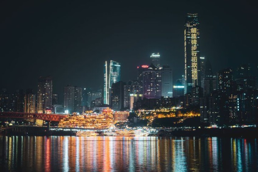 A city skyline at night with illuminated buildings reflecting on the water. 3