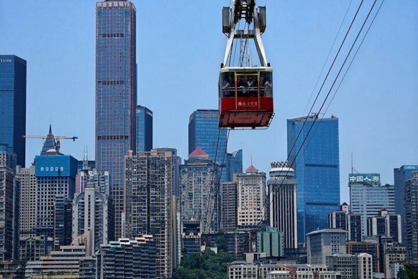 A cable car moving over a cityscape with tall buildings and construction cranes. 1