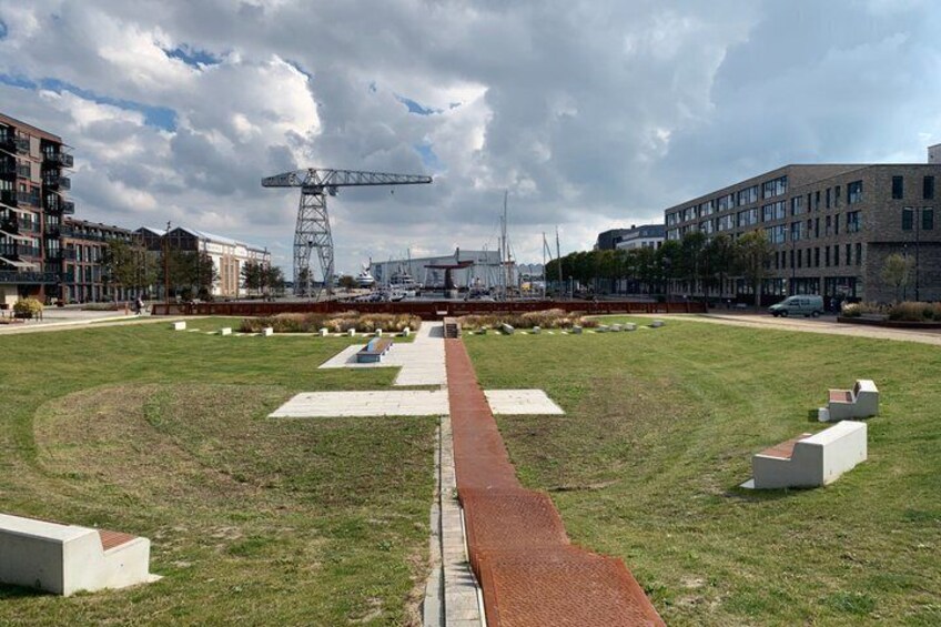 A grassy field with a red pathway, buildings, and a crane in the background. 4
