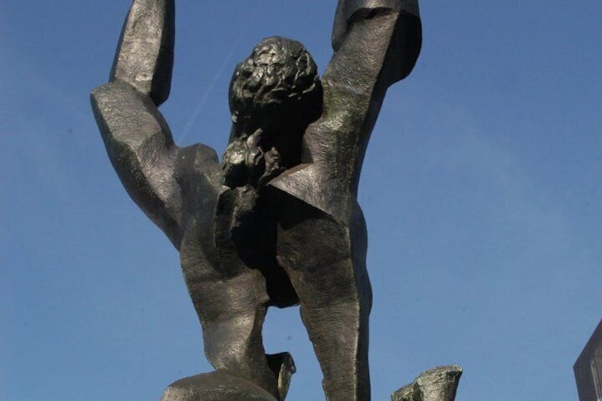 A bronze statue with raised arms, set against a clear blue sky. 2