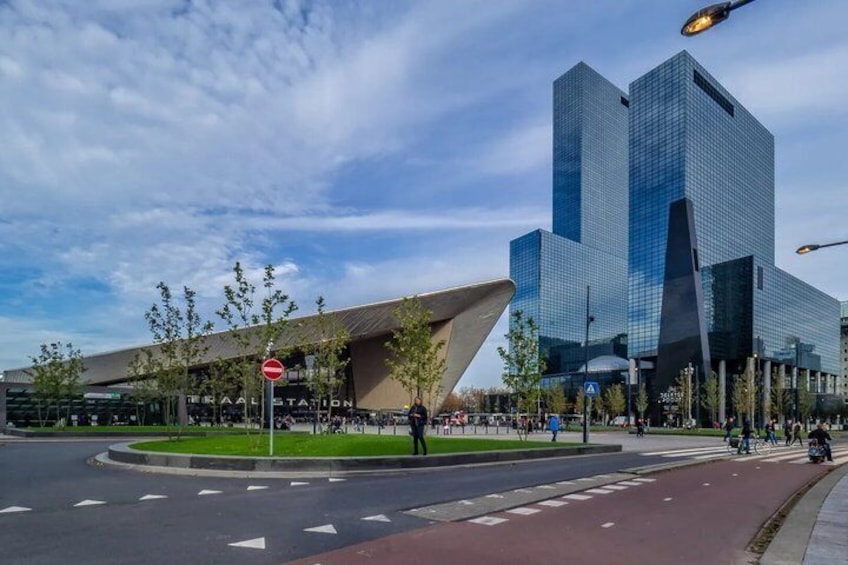 A modern building with a unique roof design, a roundabout, and a clear sky. 1