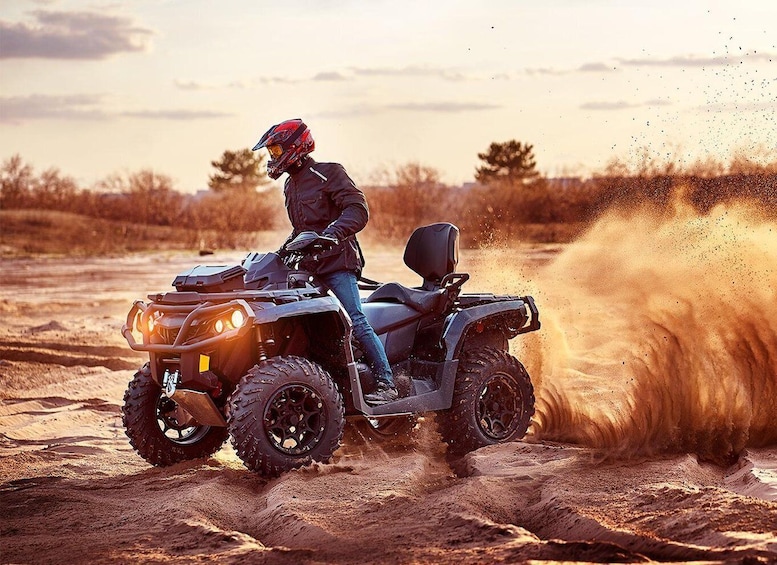A person riding an ATV on a dirt trail with dust being kicked up. 1