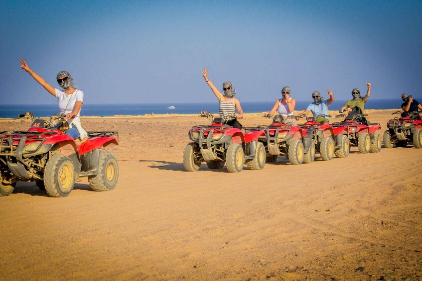 A group of people on ATVs on a sandy beach with the ocean in the background. 3