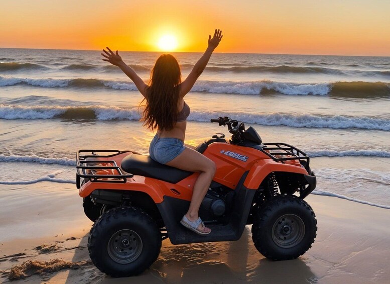A person on a quad bike on a beach at sunset. 1