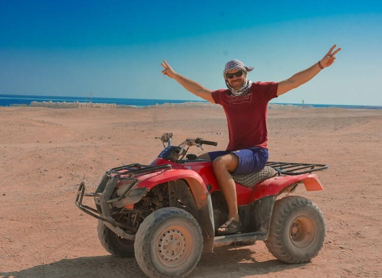 A person on a red ATV in a desert landscape with a clear sky. 3