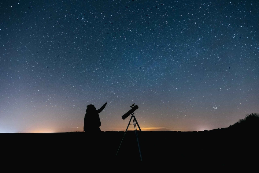 A person using a telescope under a starry night sky. 2