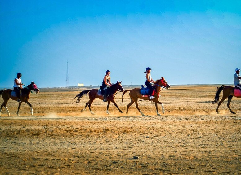 Three people riding horses in a desert landscape with a clear sky. 2