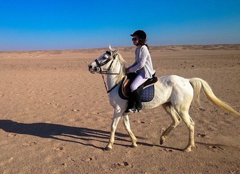 A person riding a white horse in a desert landscape. 3
