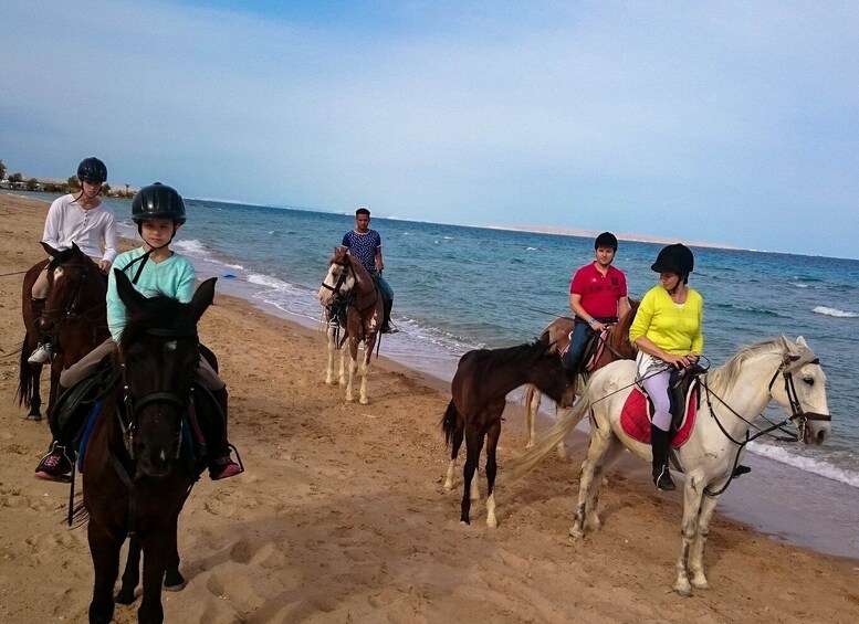 A group of people riding horses along a beach. 4