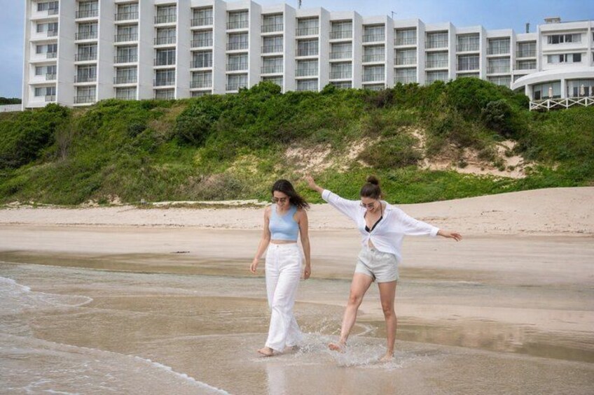 Two people walking on a beach with a hotel in the background. 2