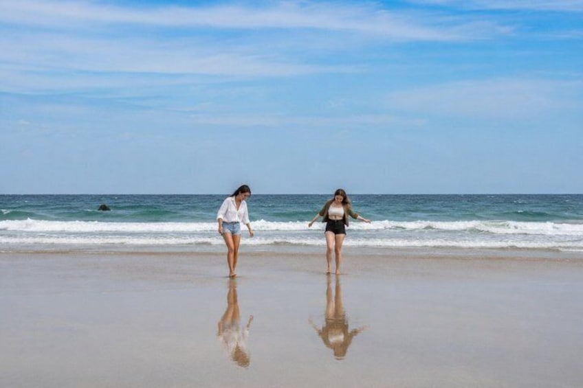 Two people walking on a beach with waves in the background. 3
