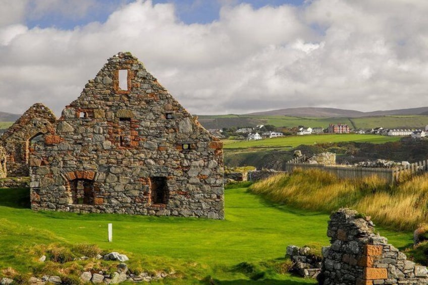 A stone ruin with a grassy field and distant houses. 3