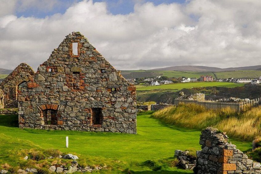 A stone ruin with a grassy field and distant houses. 4
