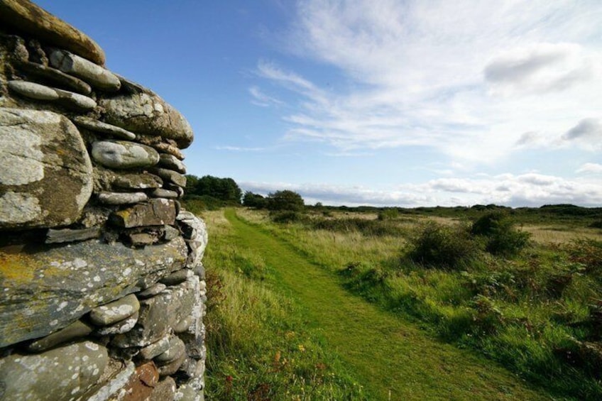 A stone wall, a grassy path, and a clear sky. 2
