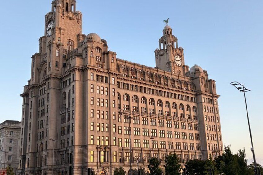 A large, historic building with multiple towers and a clock tower, featuring ornate architectural details and a prominent statue on top. 2