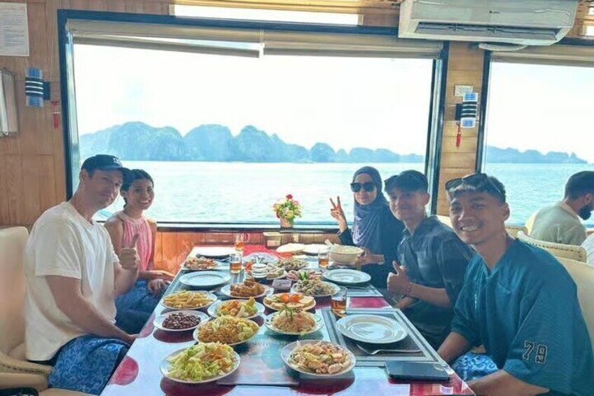 A group of people dining on a boat with a view of the water and mountains in the background. 4