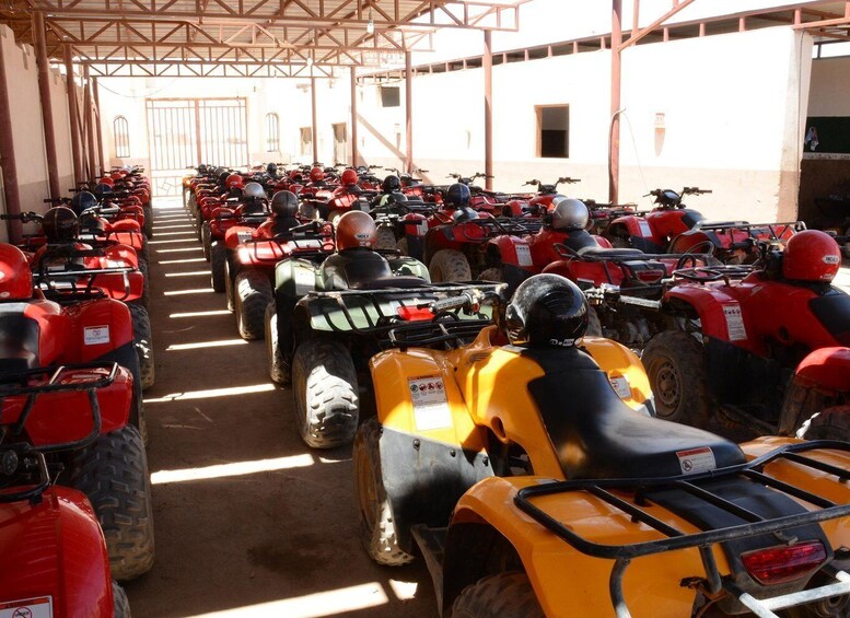 A row of ATVs parked in a covered area with a metal roof structure. 5