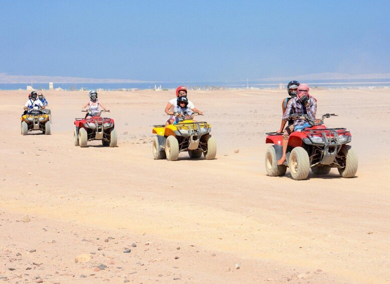 Four people riding ATVs in a desert landscape. 2