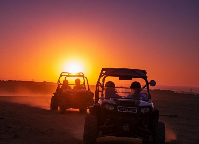 Two off-road vehicles with people driving them, silhouetted against a sunset. 4