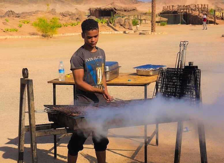 A person grilling outdoors with a portable grill and cooking utensils. 2