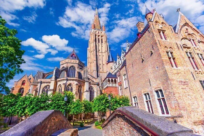 A historic church with a tall spire, intricate architecture, and a stone wall in the foreground. 4