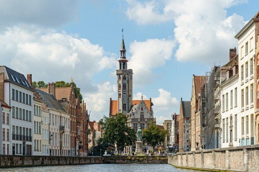 A canal with buildings on either side, a tower, and a statue in the center. 2