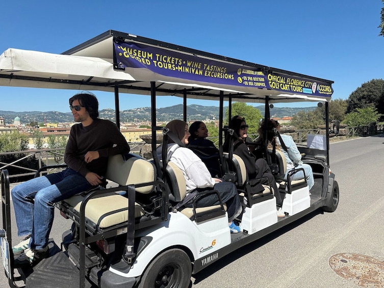 A golf cart with passengers, a banner advertising museum tickets, wine tastings, and tours. 4