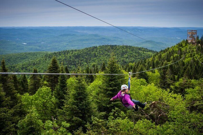 A person zip-lining through a forested mountain area. 4