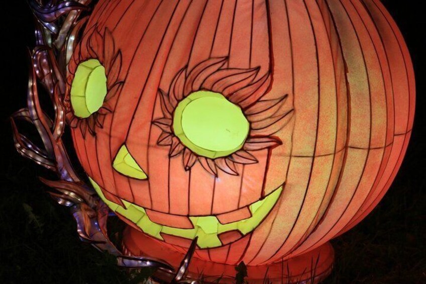 A pumpkin lantern with a carved face, green eyes, and a smiling mouth. 5