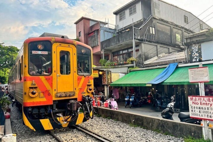 A train on tracks with a building and a sign in the background. 5