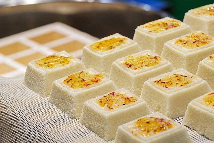 A tray of square-shaped white desserts with golden toppings. 2