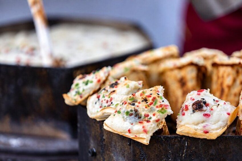 A close-up of a food item with a creamy filling and colorful toppings, possibly a pastry or dessert. 5