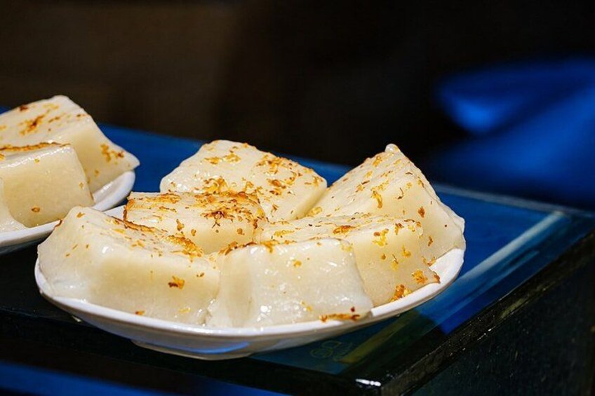 A plate of white, cubed food garnished with a yellow spice, possibly served on a blue table. 3