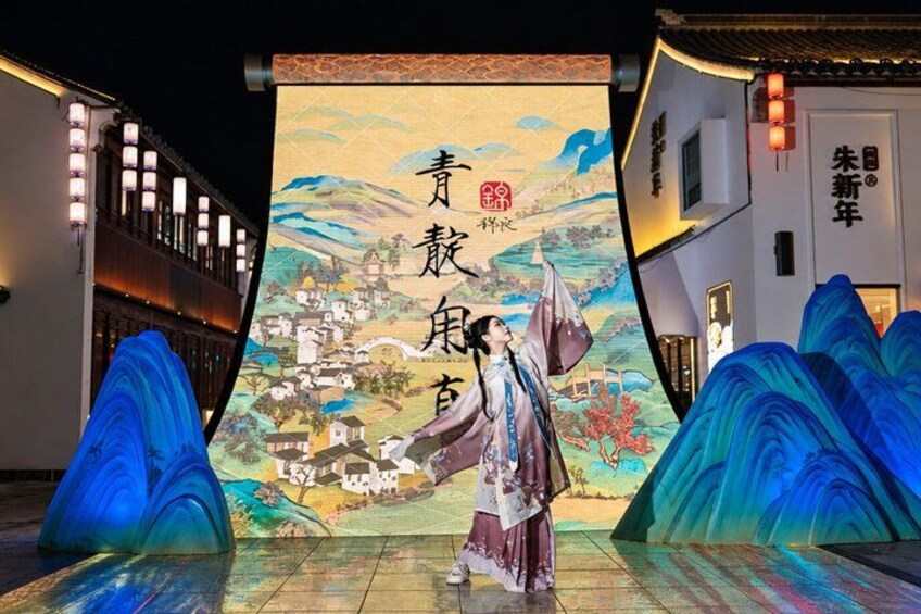 A traditional Chinese opera performance with a backdrop of a painted landscape and a performer in costume. 1