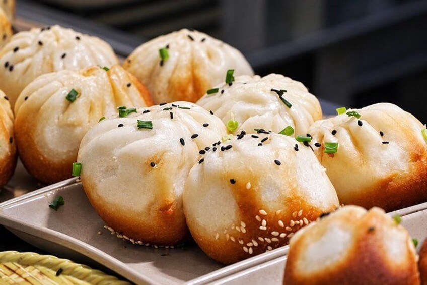 A tray of steamed buns garnished with sesame seeds and chopped green onions. 4