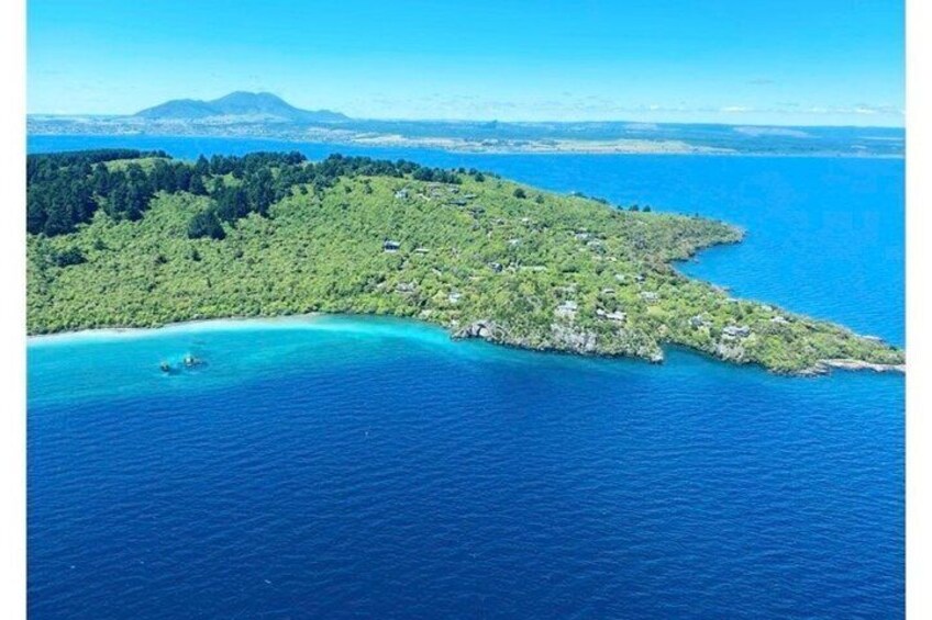 A coastal landscape with a small island, clear blue waters, and a distant mountain range. 3