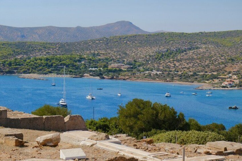 A coastal landscape with boats on the water, rocky terrain, and a hilly background. 5
