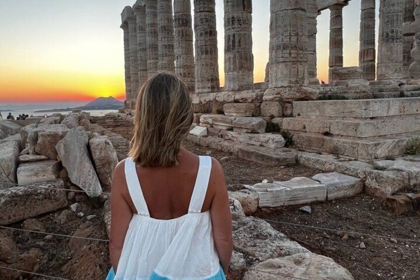 A person standing in front of ancient ruins with columns, during sunset. 2