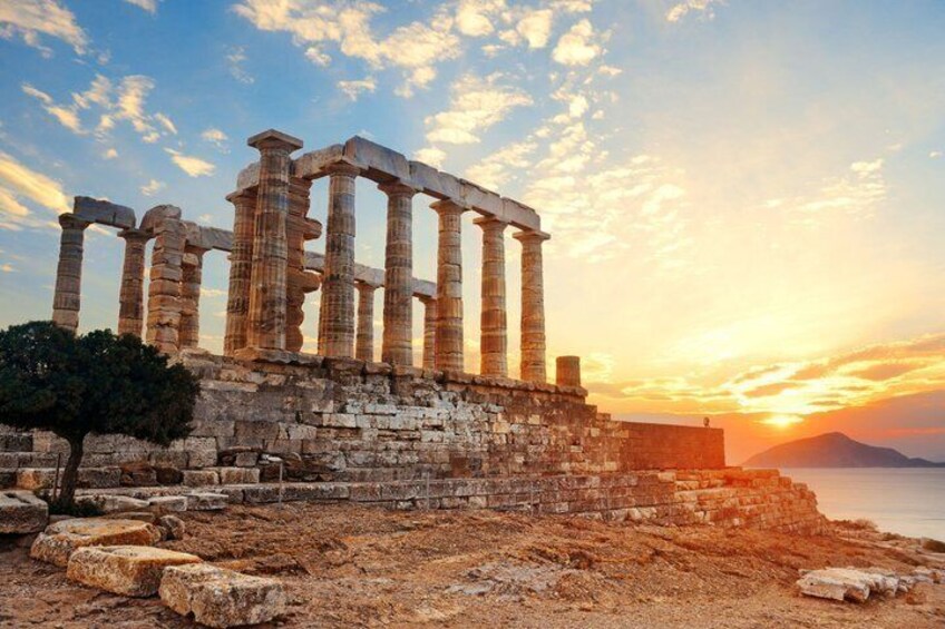Ancient ruins with columns, a tree, and a sunset over the sea. 3