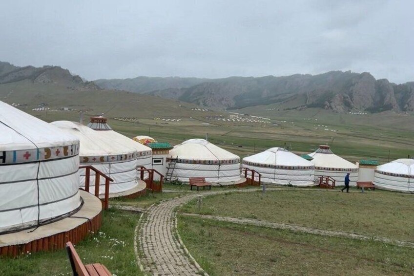 Yurts in a grassy field with mountains in the background. 4