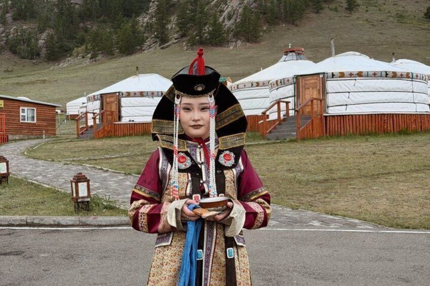 A person in traditional attire standing in front of yurts. 5