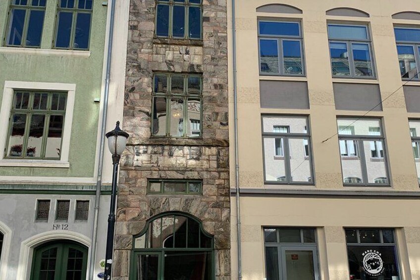 A multi-story building with a stone facade, green windows, and a street lamp. 3