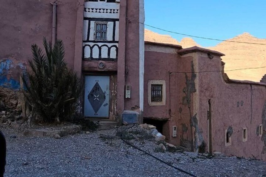 A building with a pink facade, a decorative door, and a small window. 2