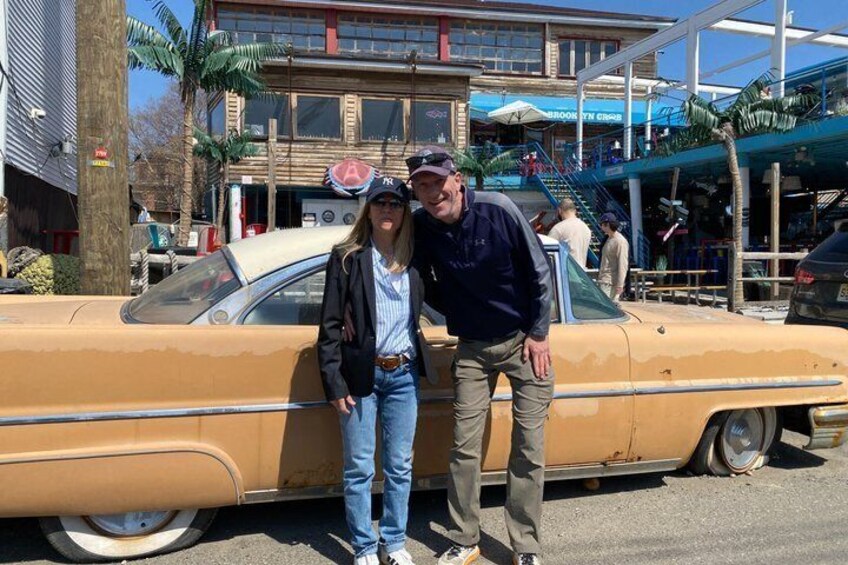 A vintage car, a building with a blue awning, and palm trees. 2