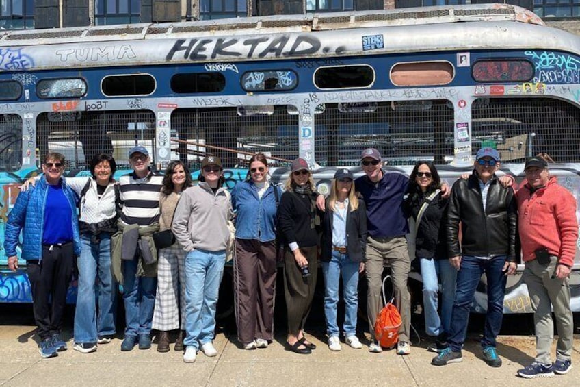 A group of people posing in front of a graffiti-covered bus with the word 'HEKTAD' on it. 4